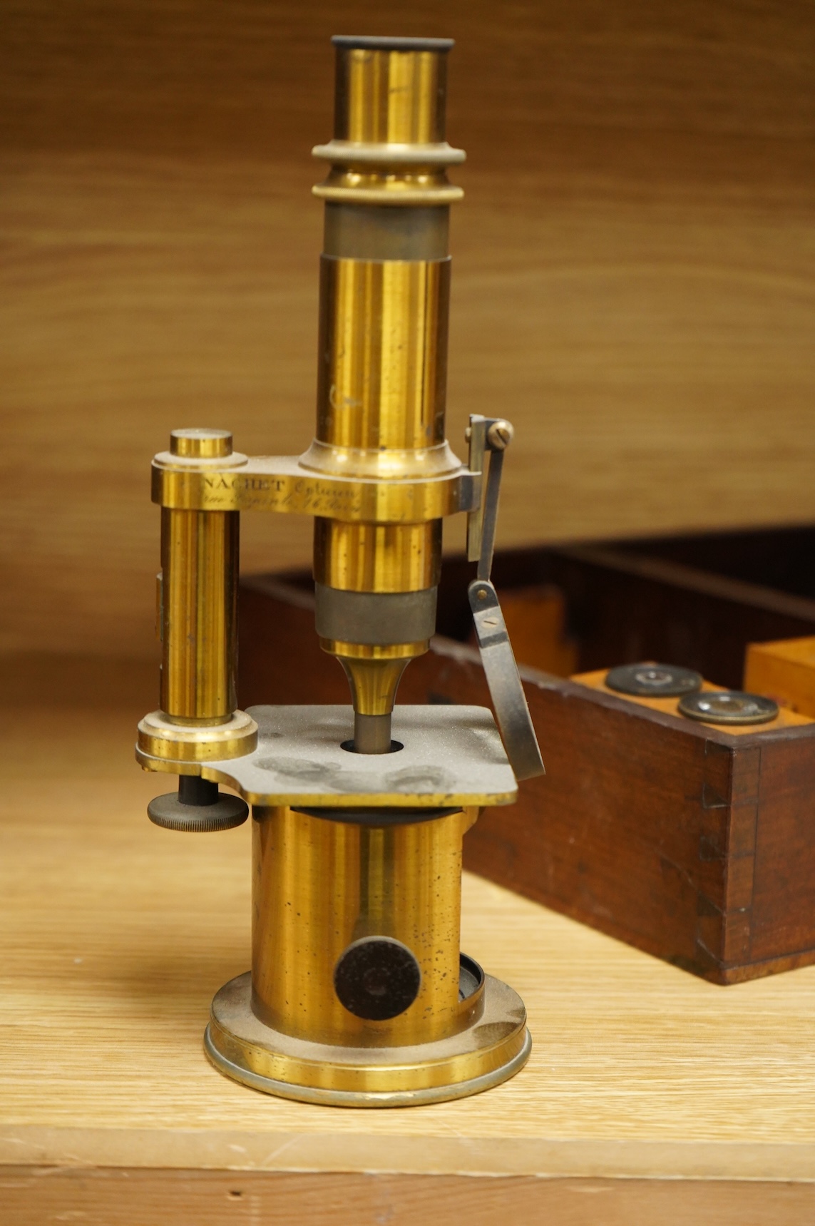 A mid 19th century French brass compound monocular microscope, by Nachet, Optician, Rue Serpente 16, Paris, with two eyepieces, three objectives and several slides, mahogany cased, instrument height 23cm